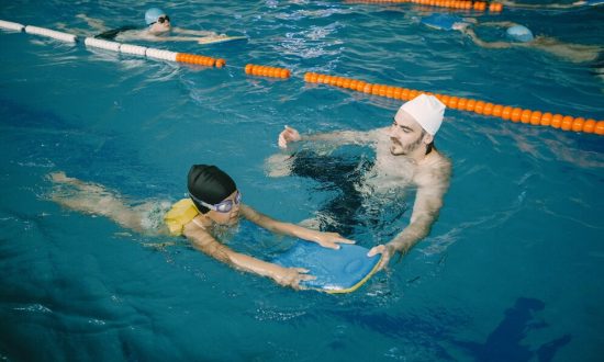 coach-teaching-kid-indoor-swimming